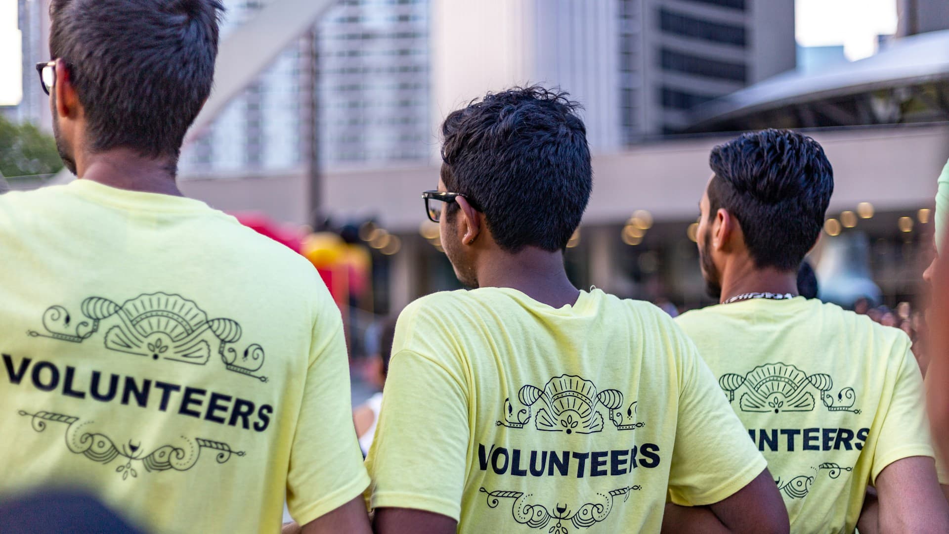 Three diverse community volunteers in yellow volunteer shirts working together to help families