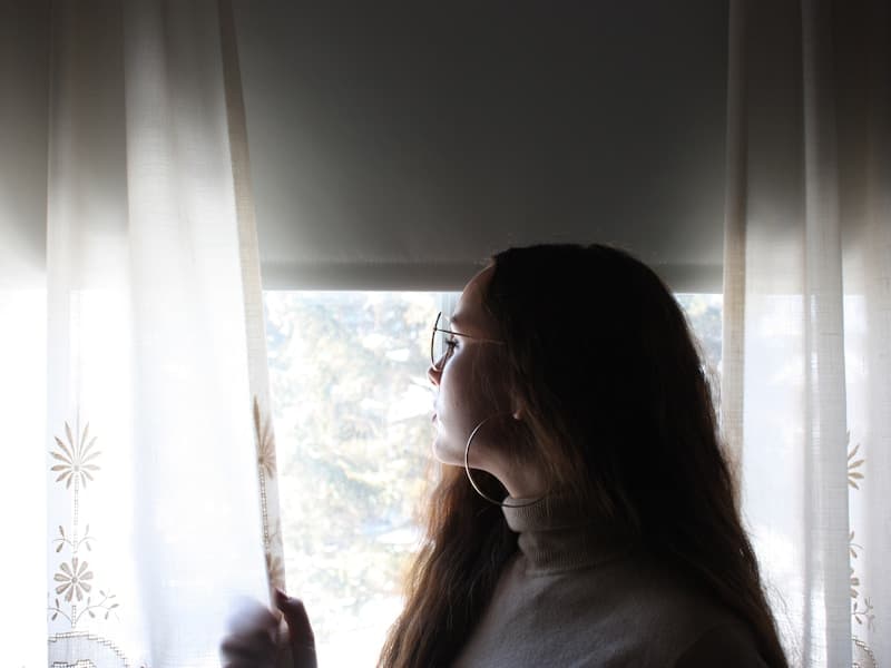 Woman standing near window in contemplative pose, representing hope and empowerment